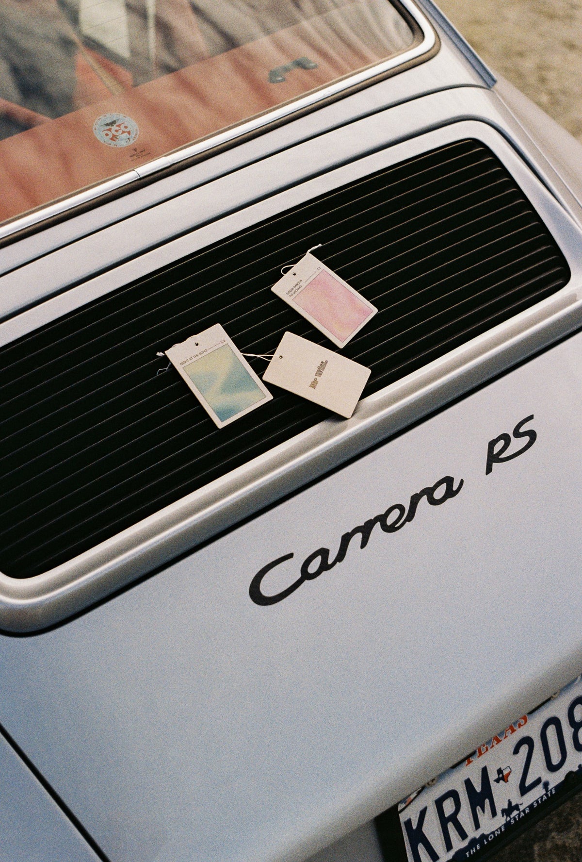 Mr Wiff air fresheners resting on the grille of a silver vintage Porsche